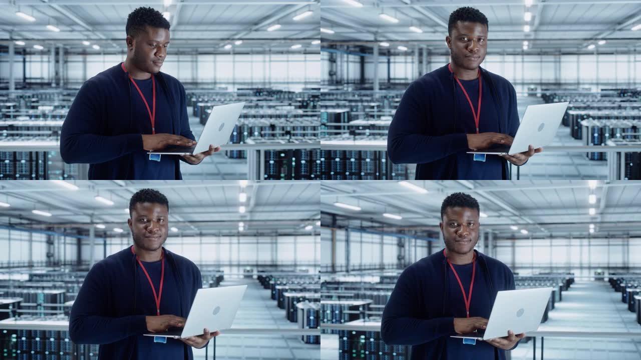 使用笔记本电脑的数据中心工程师的肖像。服务器机房专家设施，非裔美国人男性系统管理员与数据保护网络合作