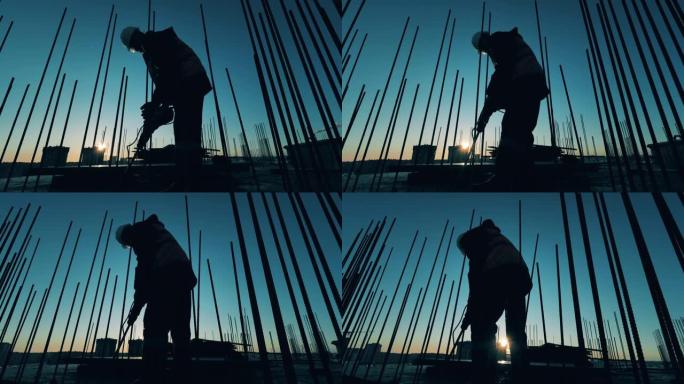 建筑工人在日落时拆除混凝土