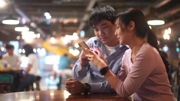年轻的东亚朋友聊天，大笑，使用手机和共享屏幕