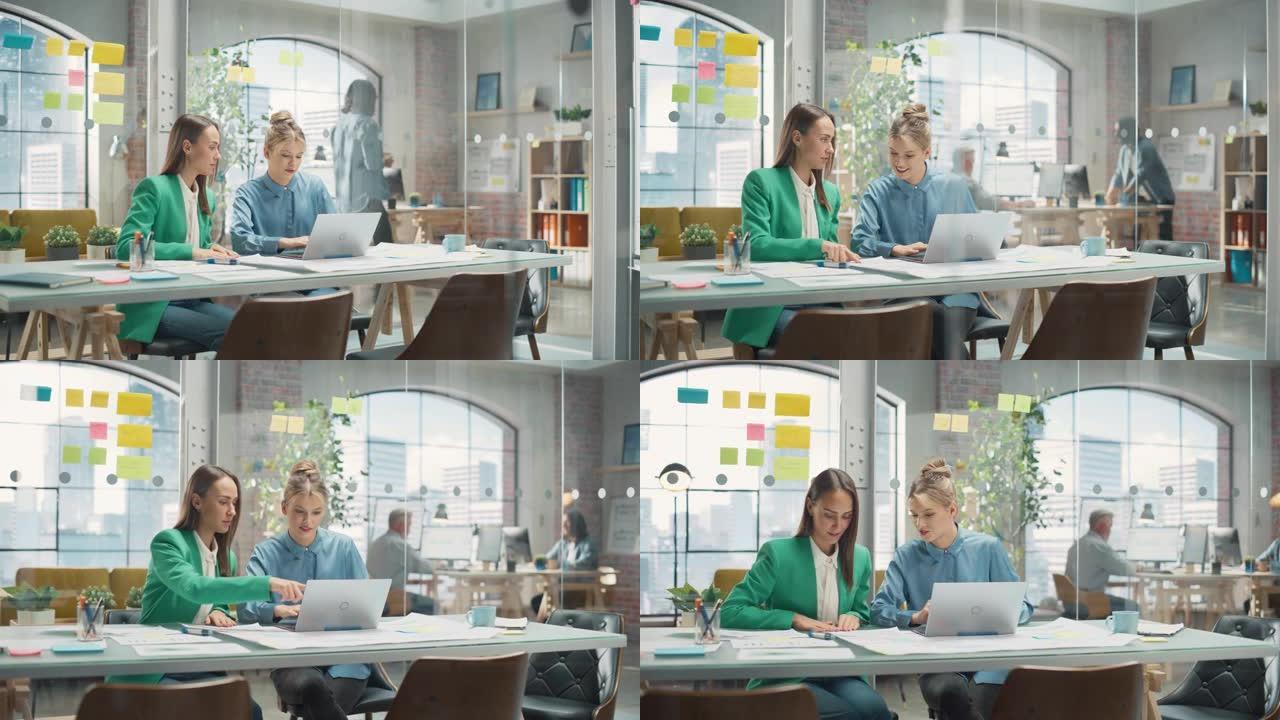 两位富有创造力的同事在Office Hub中合作并指向笔记本电脑屏幕的肖像。白人女设计师与助理讨论工