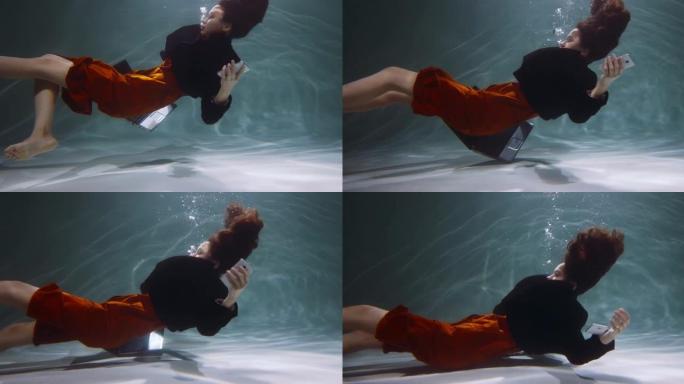 电影的侧视图，年轻的女商人沉入水下，智能手机，笔记本电脑慢动作。压力障碍概念