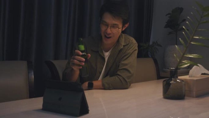 亚洲成年男子在家时通过在线视频通话虚拟聚会与朋友一起喝啤酒