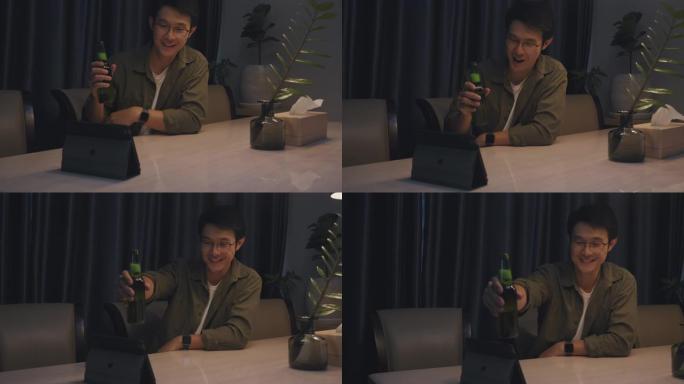 亚洲成年男子在家时通过在线视频通话虚拟聚会与朋友一起喝啤酒