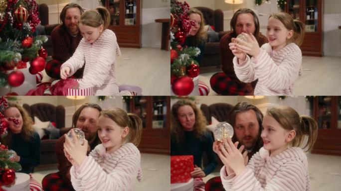 女孩在圣诞节打开魔术雪球