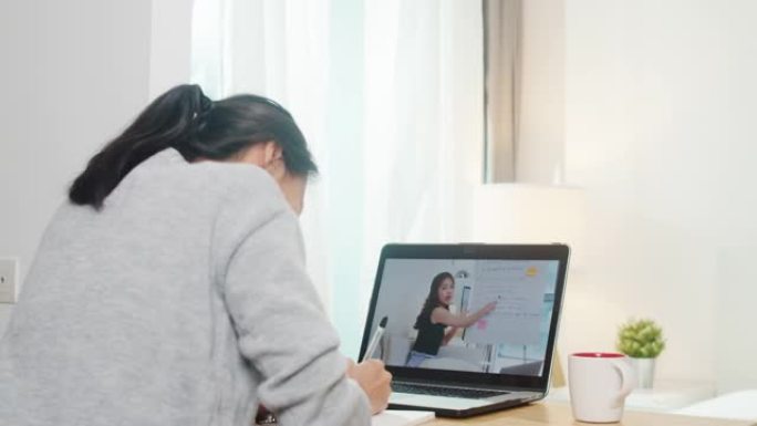 年轻的亚洲青少年女大学生使用笔记本电脑远程学习课与女教师在家上网远程教学。