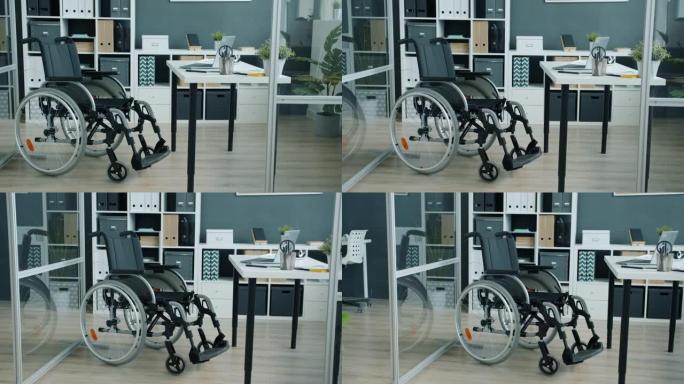 桌子附近的现代玻璃墙办公室，带轮椅，适合残疾人使用