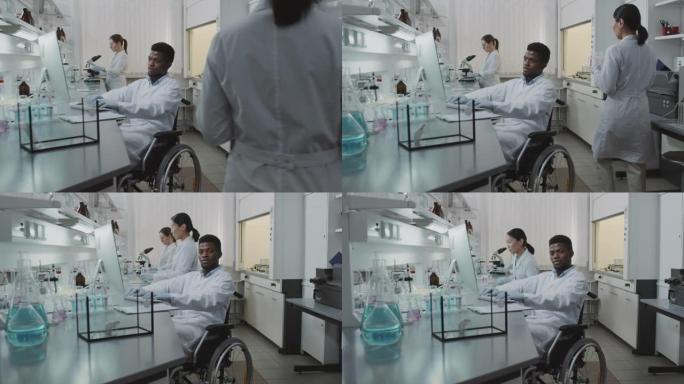 坐在轮椅上的男性科学家在实验室工作并摆姿势