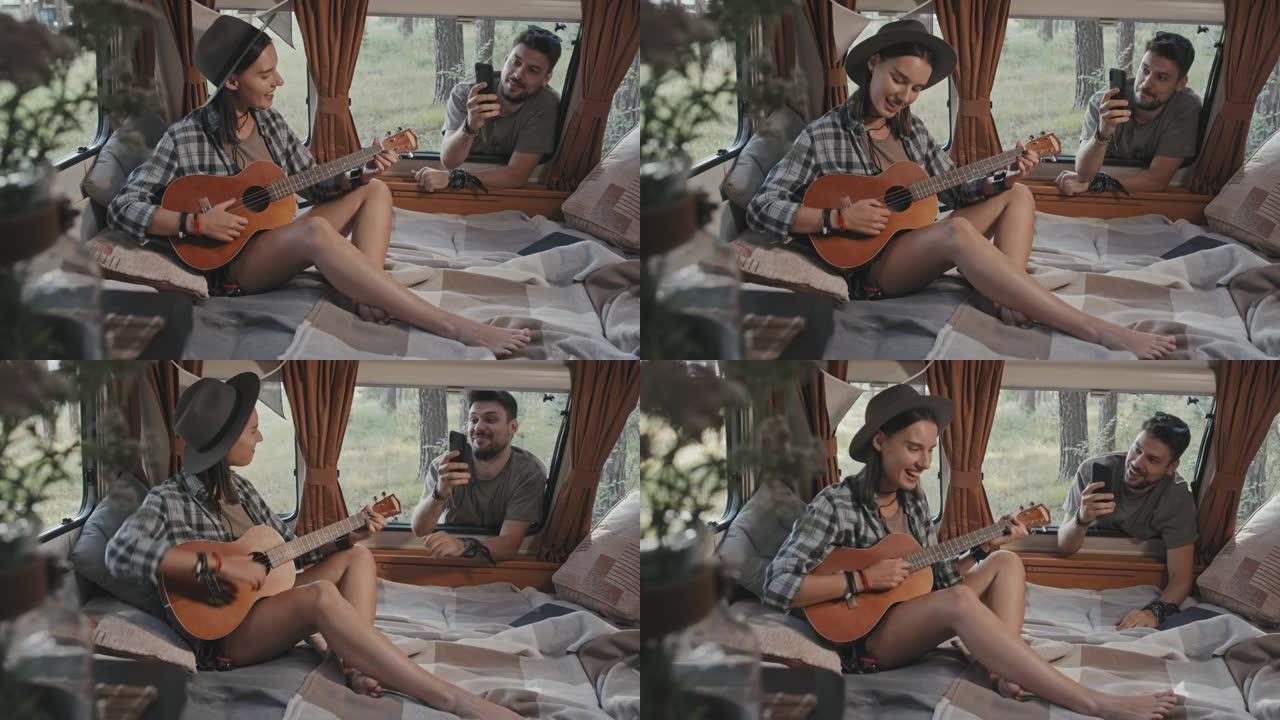 男子在露营车中拍摄女子演奏夏威夷四弦琴