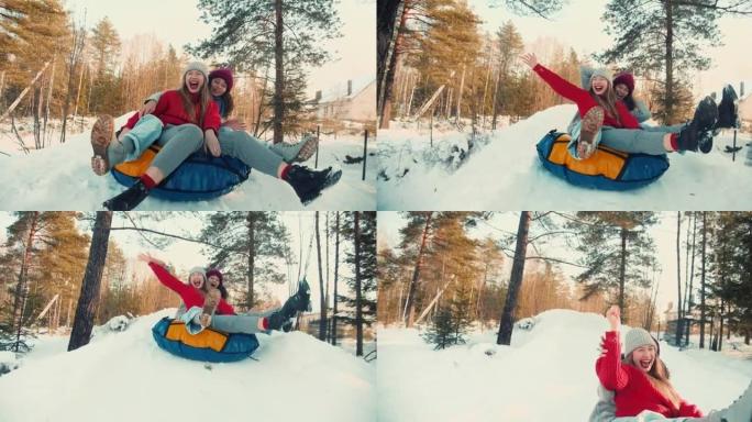 两个多民族兴奋快乐美丽的朋友女人微笑雪橇在雪坡上对着镜头，冬天有趣的慢动作。