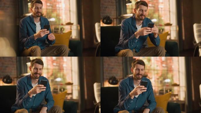 一个英俊的男人坐在沙发上的肖像，在时尚的阁楼公寓或咖啡馆里使用智能手机。富有创造力的男性微笑，检查社