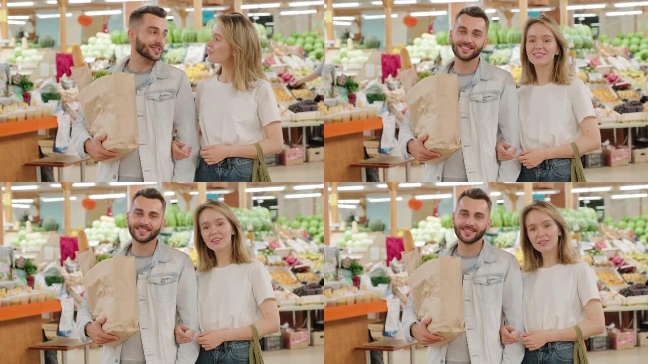 快乐的夫妇带着纸袋在市场上摆姿势