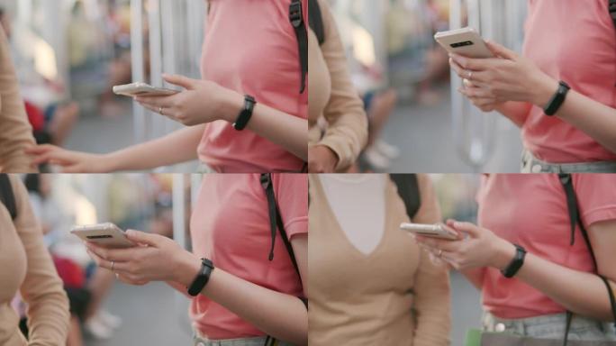 SLO MO两名亚洲妇女在火车上旅行时使用智能手机，特写镜头