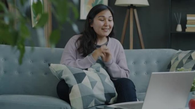 快乐的年轻女子用笔记本电脑在家室内分享好消息进行视频通话的肖像