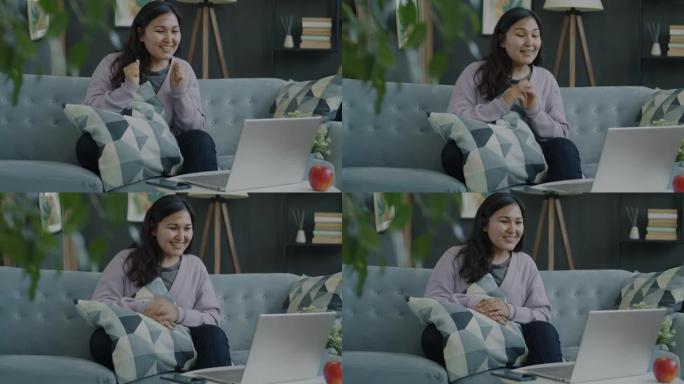 快乐的年轻女子用笔记本电脑在家室内分享好消息进行视频通话的肖像