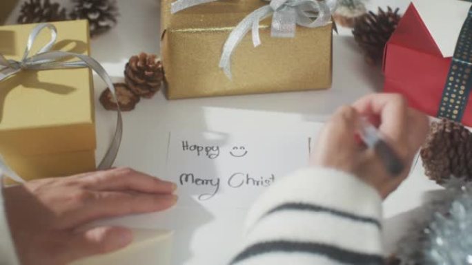 女孩手在桌子上写贺卡冬季圣诞装饰品的特写。