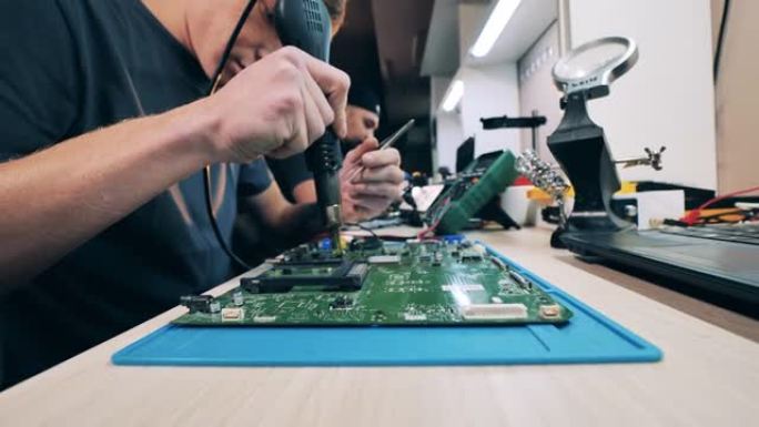 技术人员使用热风枪修理笔记本电脑系统板