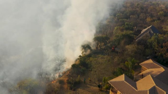 气候紧急情况。在非洲南部一个住宅区附近燃烧的草火的空中特写镜头。火灾是由干旱和气候变化引起的