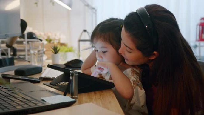 在线孕妇老师妇女教第一个孩子女儿使用数字平板电脑在家玩教育活动游戏。母亲爱孩子。设置儿童平板电脑的时