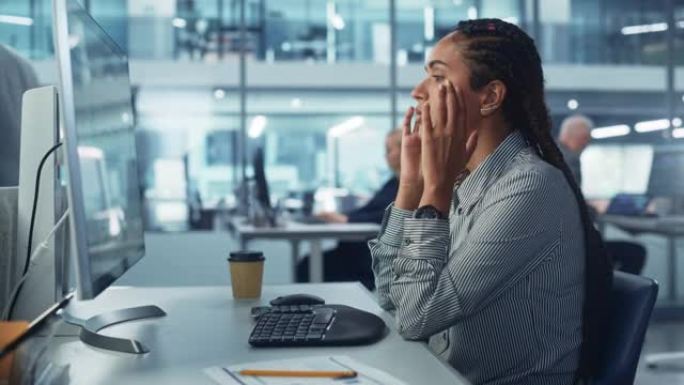 黑人女性公司办公室工作人员感到压力，沮丧在台式计算机上起作用。会计师感到项目压力，按摩头部，进行统计