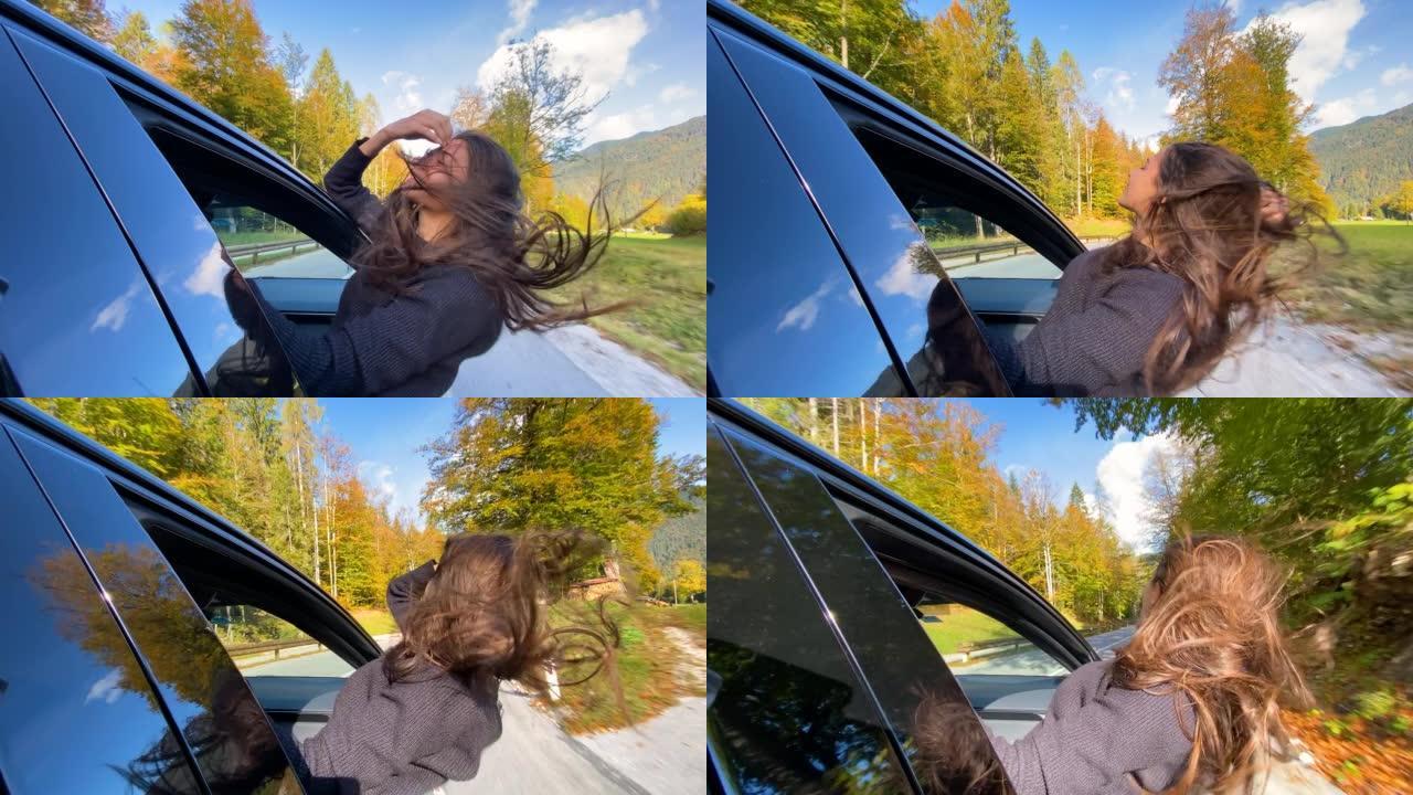女人开车穿过五颜六色的秋天森林时玩得开心