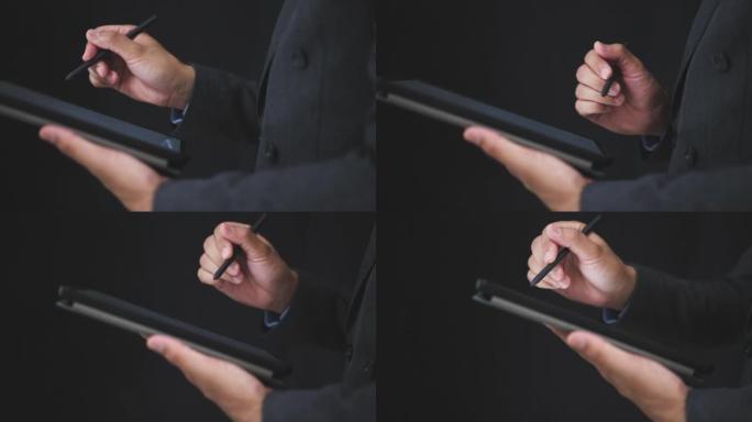 黑色西装上的商人使用数字笔触摸黑色背景色调的数字平板电脑