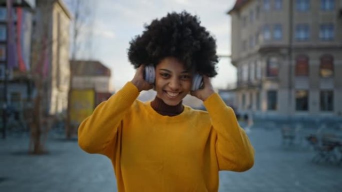 快乐的年轻女子在城市通过耳机听音乐
