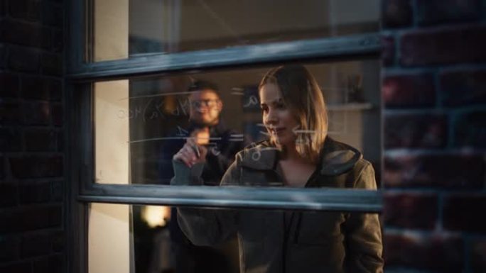 白人年轻女性通过使用可擦除的玻璃标记在家里的窗户上向男性朋友解释数学方程式。两个多民族的未来工程师一