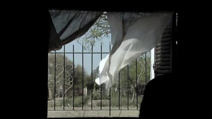 在阿根廷一所简陋的乡村房子里，窗帘从敞开的窗户里随风飘动。