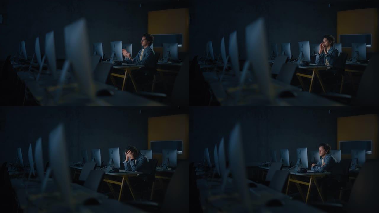 紧张的男学生独自坐在大学信息学室，晚上在计算机科学项目上工作。累了的学者在大学里用电脑研究它，写作业