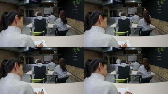 理论课上烹饪学生的后视图向教室前面的女老师提问