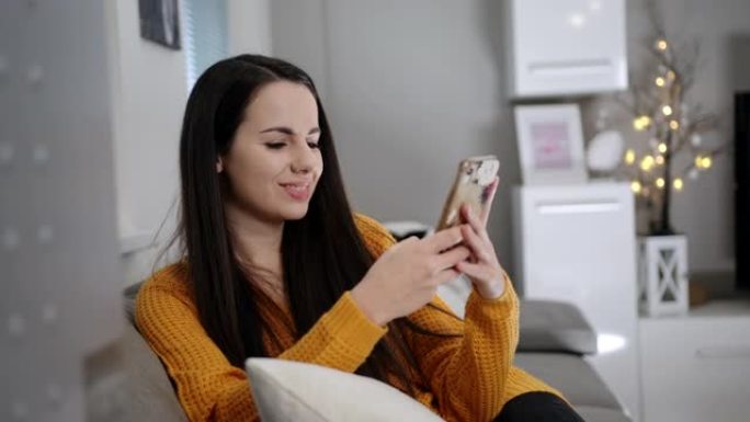 WS年轻女子在家中沙发上使用智能手机时感到高兴