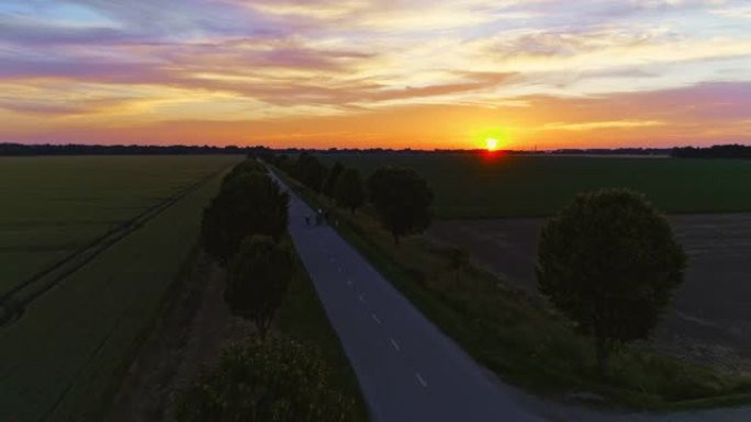 日落时分在乡间小路上骑自行车的空中人群