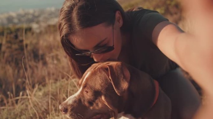 4k视频片段，一位迷人的年轻女子在与狗一起远足时自拍