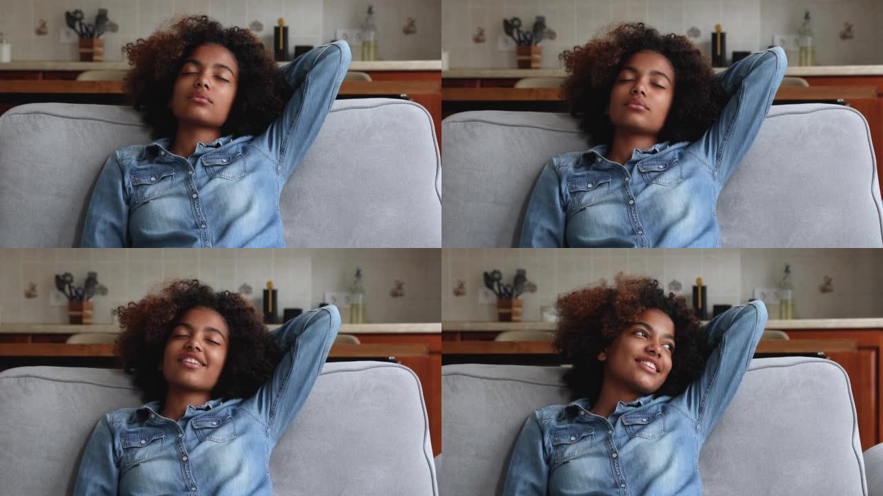 平静的千禧一代美国黑人妇女在沙发上享受宁静的休息