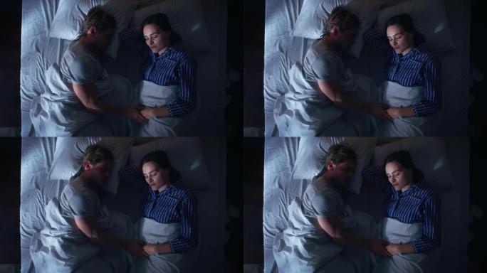 顶视图家: 幸福的年轻夫妇晚上睡在床上。漂亮的女朋友和帅气的男朋友睡在一起。两口之家相向而睡。中拍上