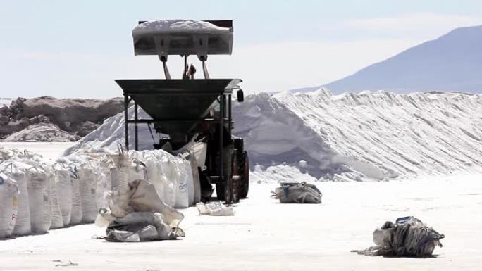 盐生产，装载机车辆在南美洲阿根廷萨尔塔省萨利纳斯·格兰德斯盐滩的盐矿床中装盐。放大。4k分辨率。