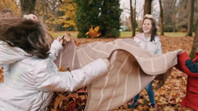 孩子们在公园里拿着秋叶毯子