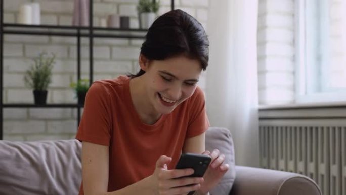 美丽的千禧女孩嘲笑智能手机上有趣的视频内容。