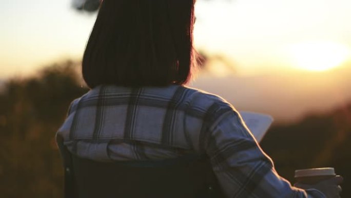 日落时分，女人在山上用咖啡杯户外放松