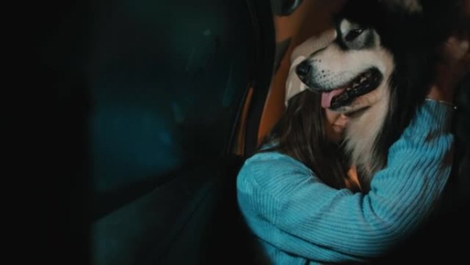戴着羊毛帽子的年轻女子和她的狗坐在汽车后座上