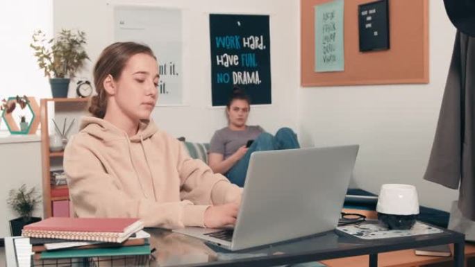 大学生使用笔记本电脑并与室友交谈