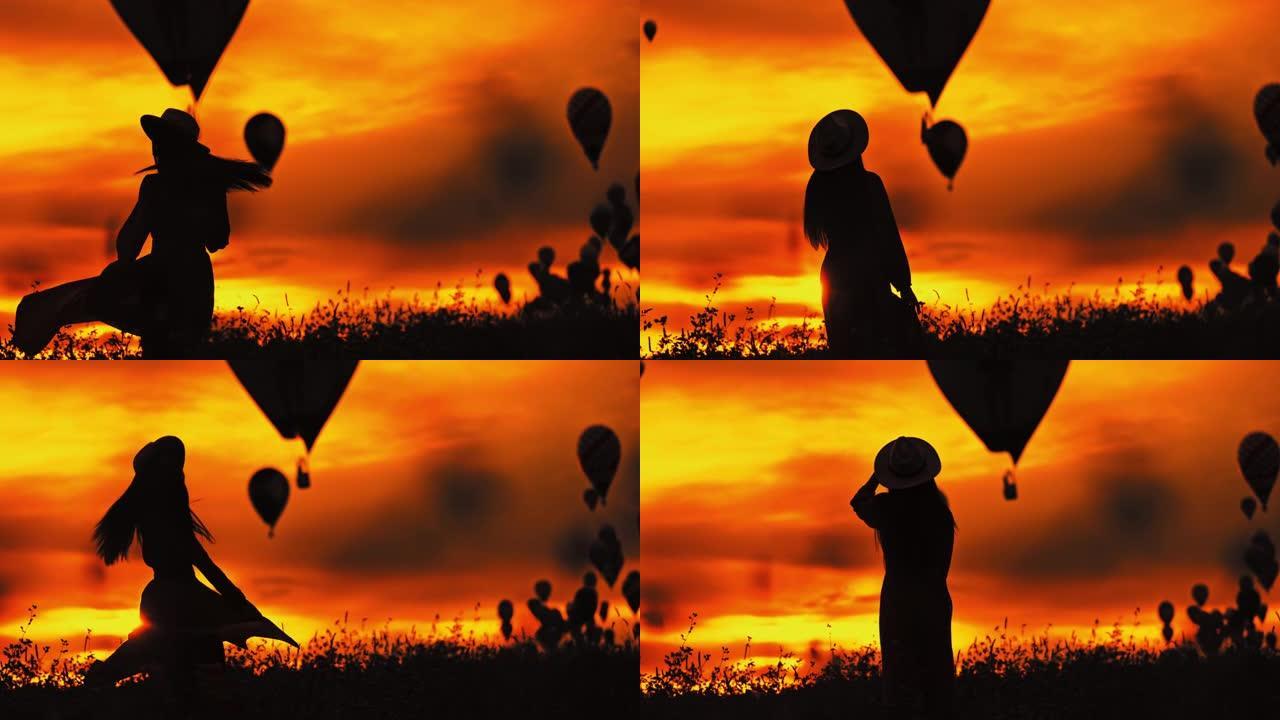 WS的剪影，一个无忧无虑的女人在野外旋转，在日落时天空中有热气球