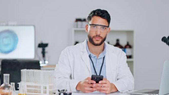 快乐的科学家通过电话研究统计和医学期刊，戴着安全眼镜和实验服。年轻的男性化学家或医学研究人员检查数据
