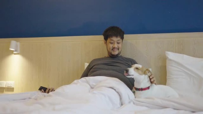 用智能手机将他的狗叫到床上的亚洲大男人的两张照片