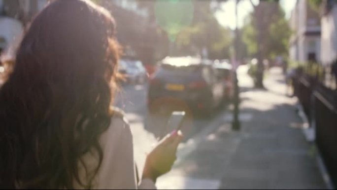 4k后视录像，一名年轻女子在城市外面散步时使用手机