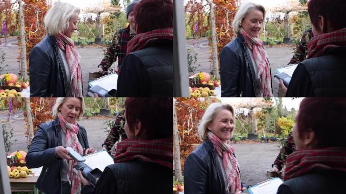微笑的成熟女性顾客在苗圃购买植物