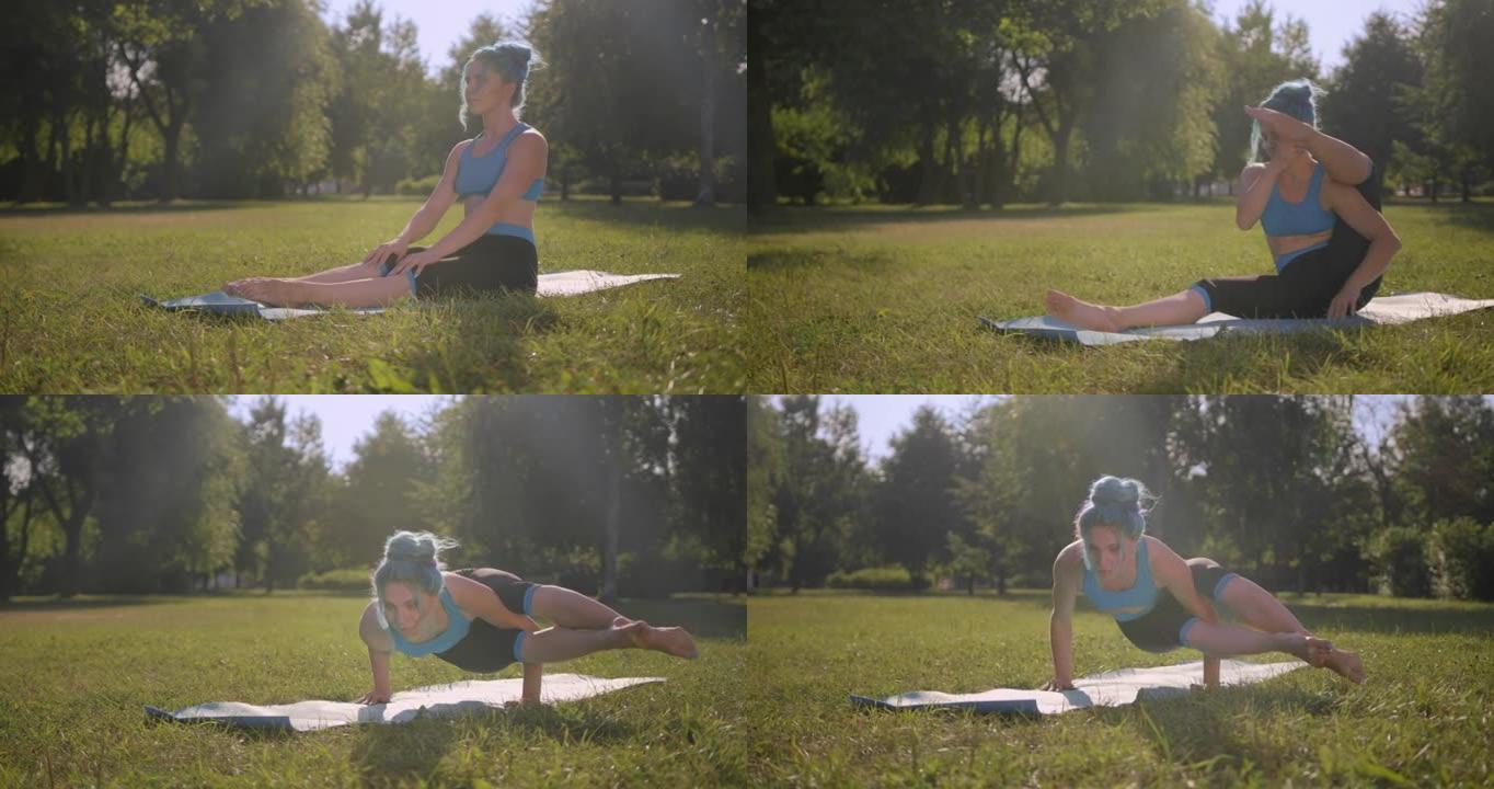 一个年轻迷人的绿松石头发的女人在阳光下在公园的瑜伽垫上锻炼