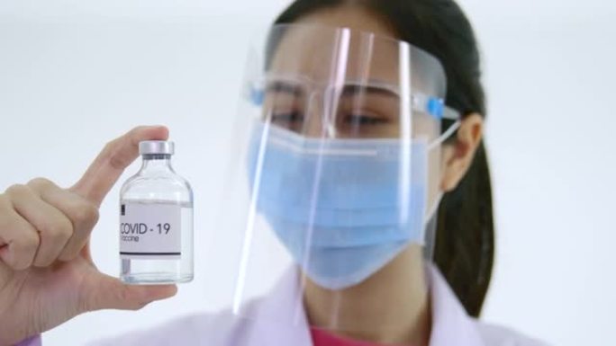一位年轻的女医生为新型冠状病毒肺炎拿起疫苗瓶的焦点传达了一种希望，即疫苗可以通过平移和利用侧面的光线