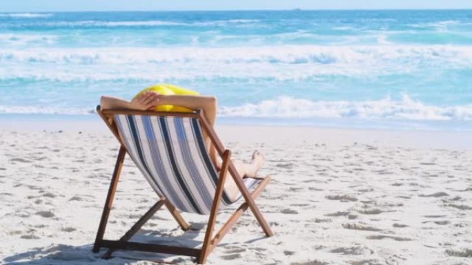 女人在海岸度假期间在海滩上放松和欣赏风景。一名妇女在暑假，空闲时间和在热带度假胜地度假时独自躺在躺椅