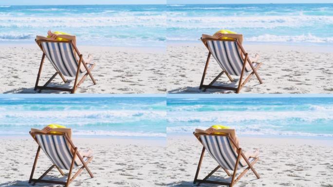 女人在海岸度假期间在海滩上放松和欣赏风景。一名妇女在暑假，空闲时间和在热带度假胜地度假时独自躺在躺椅